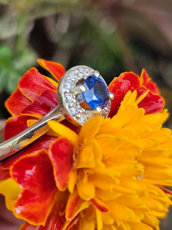 Hand wearing a ring with a blue gemstone