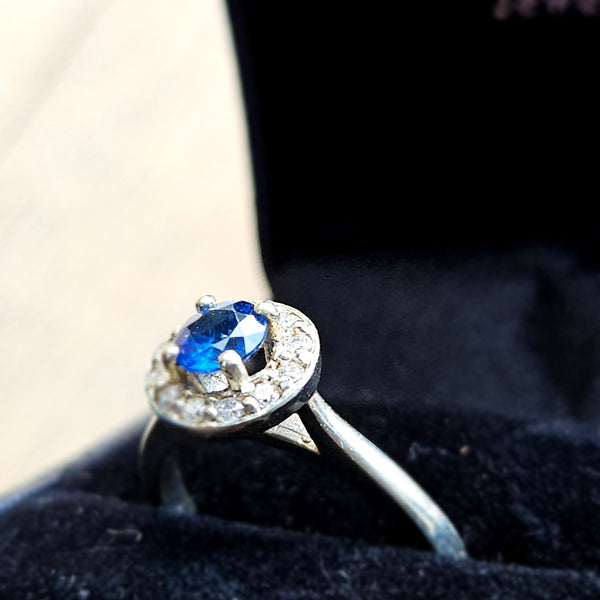 Hand wearing a ring with a blue gemstone