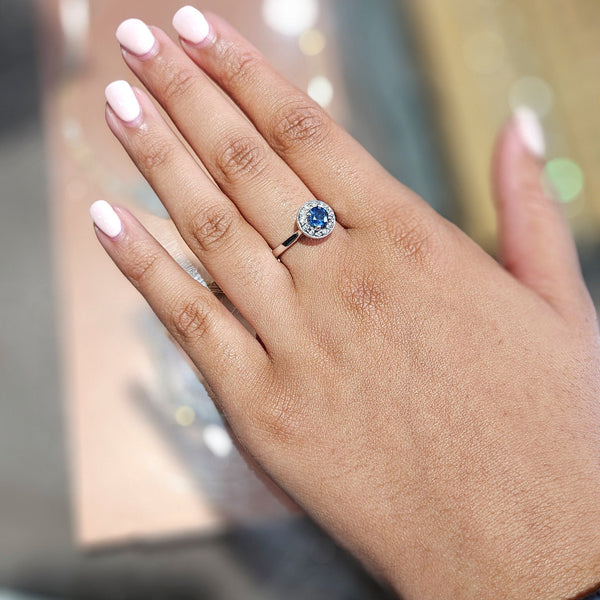 Hand wearing a ring with a blue gemstone