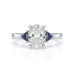 Oval trilogy engagement ring with trillion shaped blue sapphire side stones