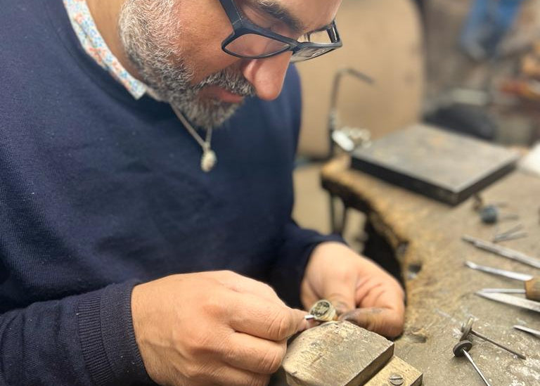 Man working on a small metal object in a workshop